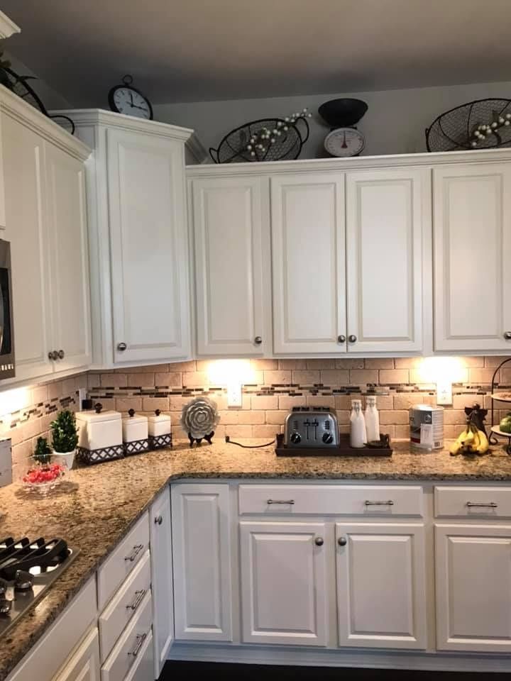 Bright kitchen with white cabinets, granite countertops, and under-cabinet lighting, countertop appliances, and decor.