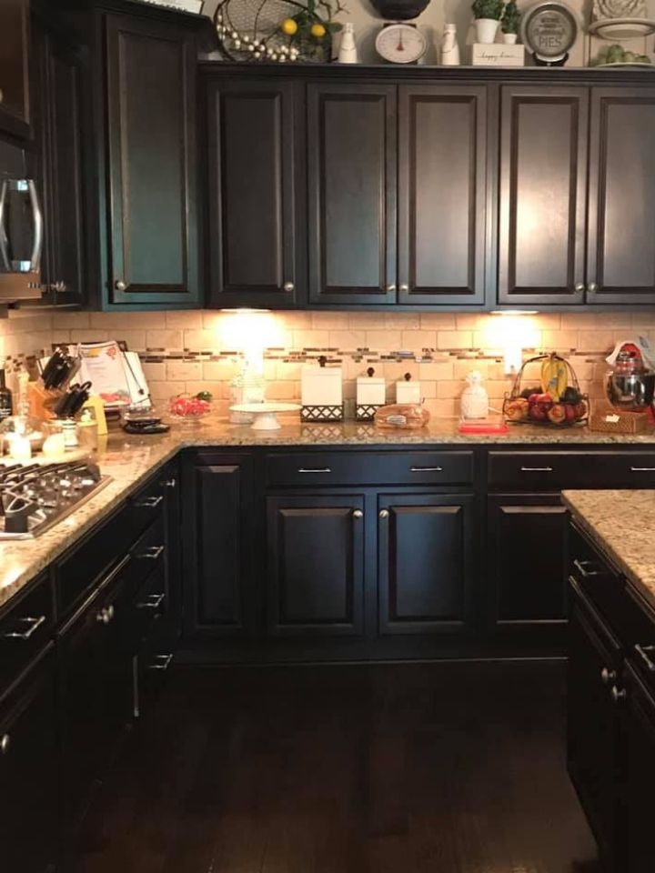 Modern kitchen with dark cabinets, granite countertops, and warm under-cabinet lighting