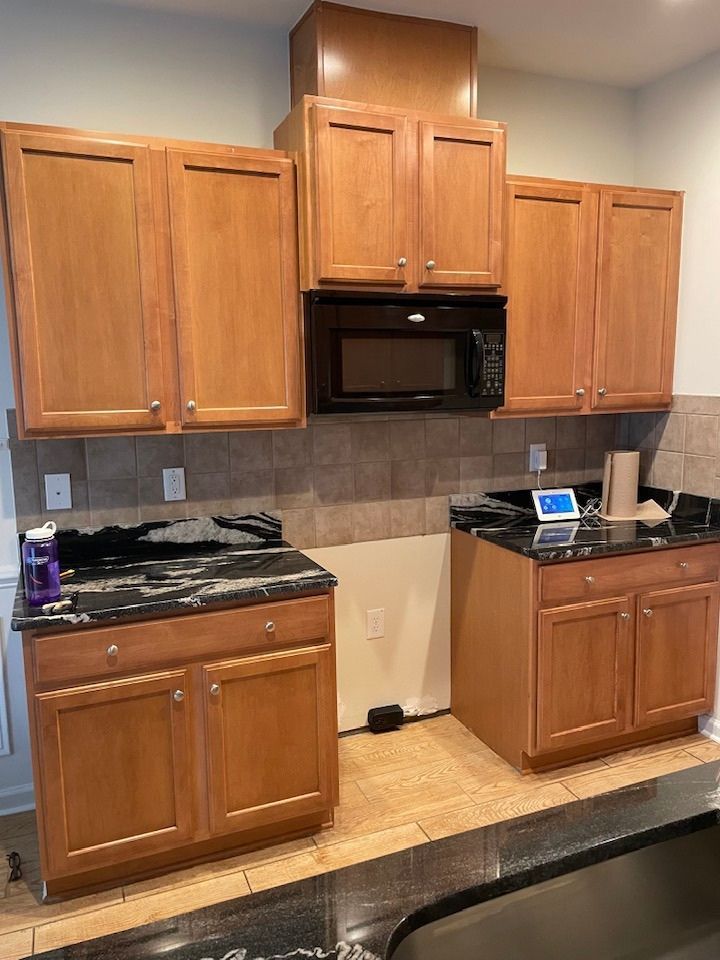 Kitchen with wooden cabinets, black appliances, and a stainless sink counter.