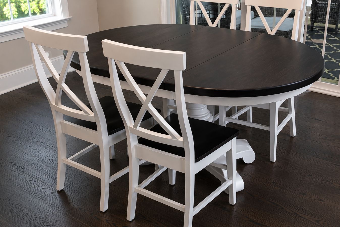 Black oval dining table with white chairs in a bright room