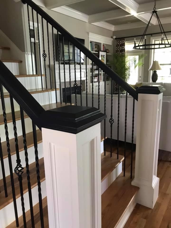 Modern staircase with black railings, white posts, and wood steps in a bright home interior