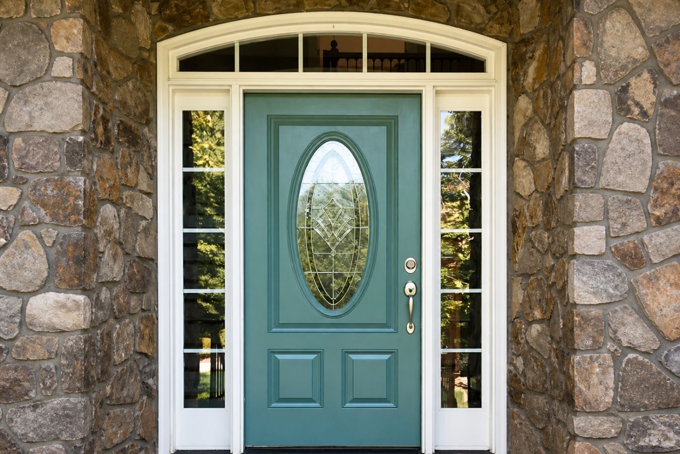 Teal front door with oval glass panel, framed by white trim and stone exterior walls.