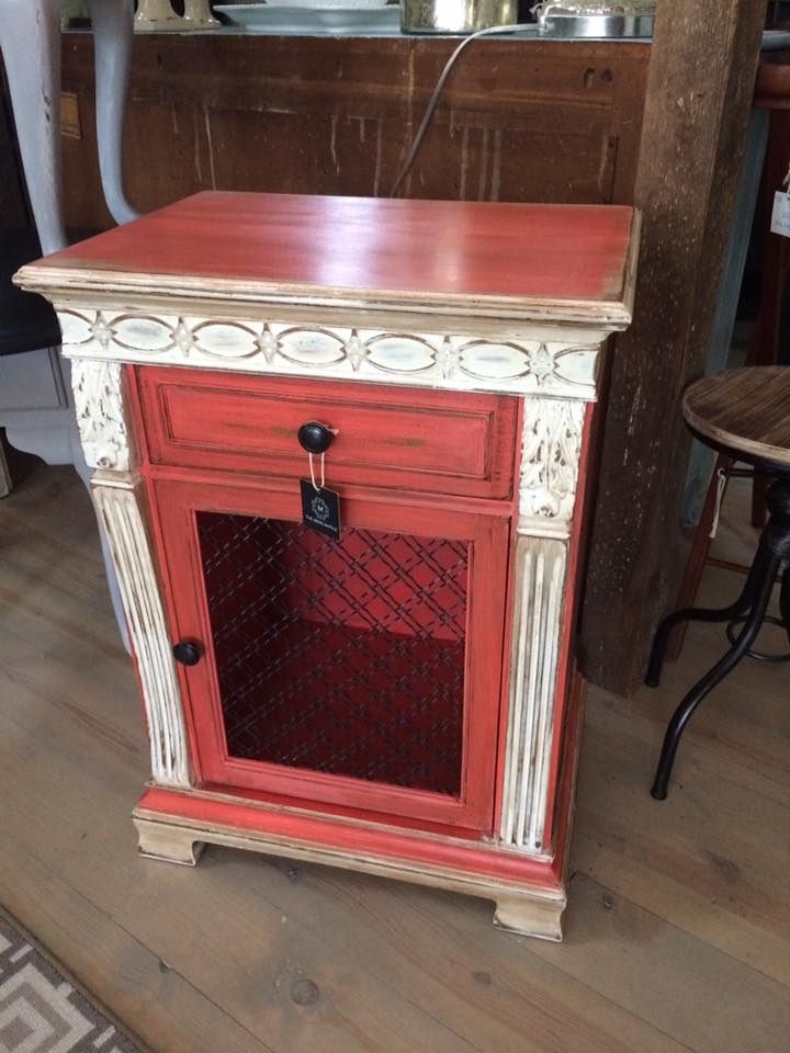 Red vintage cabinet with decorative trim and mesh door on a wooden floor