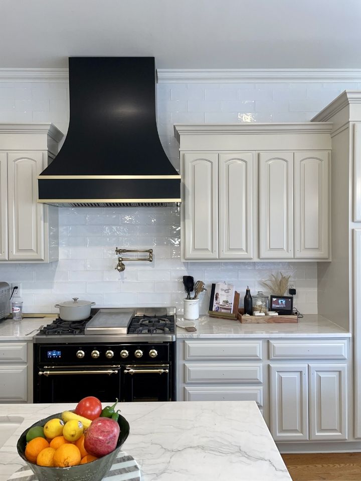 Modern kitchen with white cabinets, black range hood, and fruit bowl on marble island