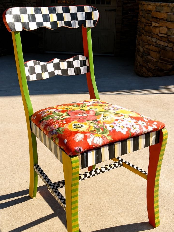 Colorful chair with checkered back and floral seat, painted green legs, sitting outdoors in sunlight