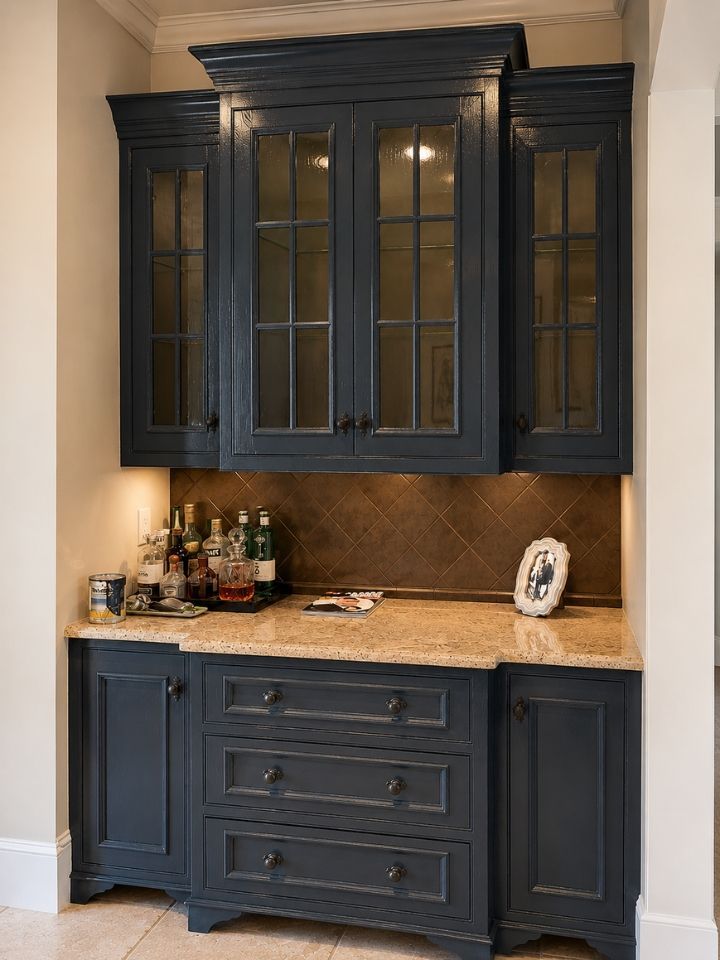 Built-in dark blue cabinetry with glass upper doors, granite countertop, and backsplash in a kitchen nook