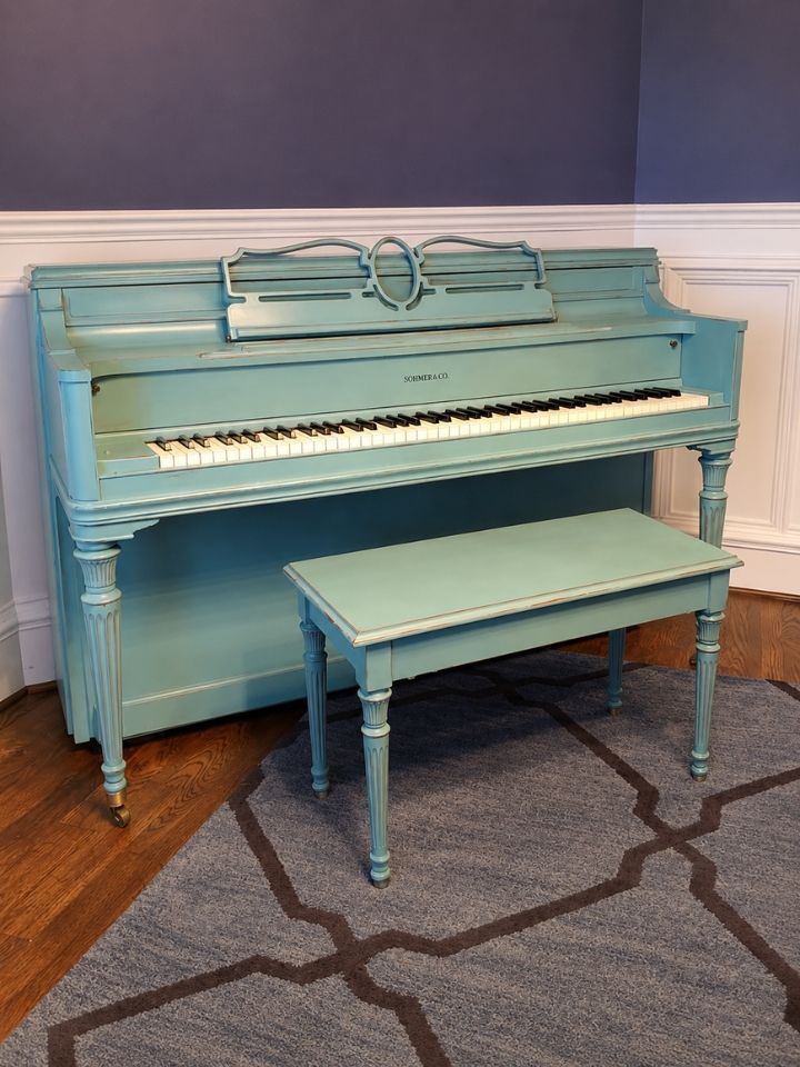 Vintage light-blue upright piano with matching bench in a room with hardwood floor and gray rug