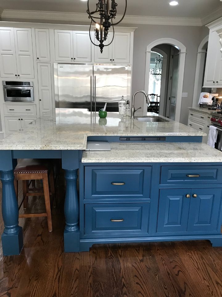 Bright kitchen with blue island cabinets, white marble counters, stainless appliances, and hardwood floors.