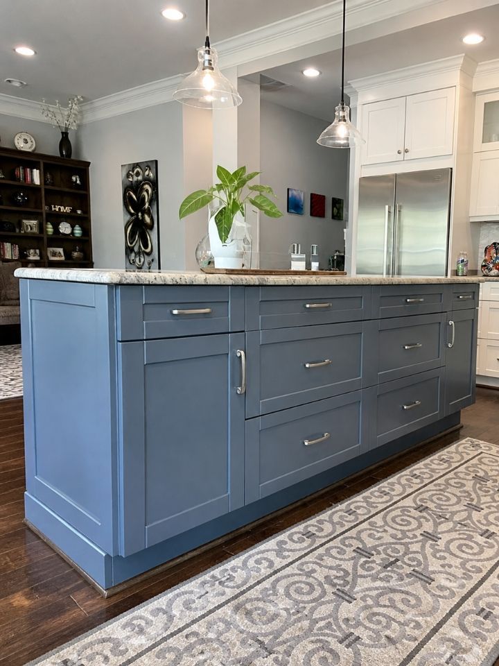 Blue kitchen island with drawers and silver handles in a bright modern kitchen