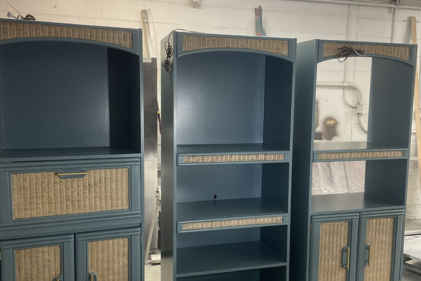 Three blue painted shelving cabinets with woven basket drawers, lined up against a wall.