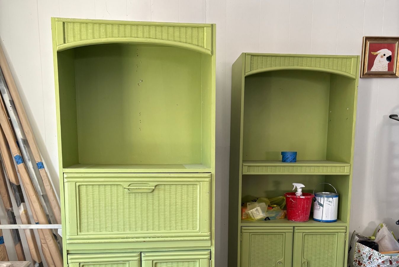 Two lime-green wicker cabinets with shelves, holding small items in a room with white wall and ladder.