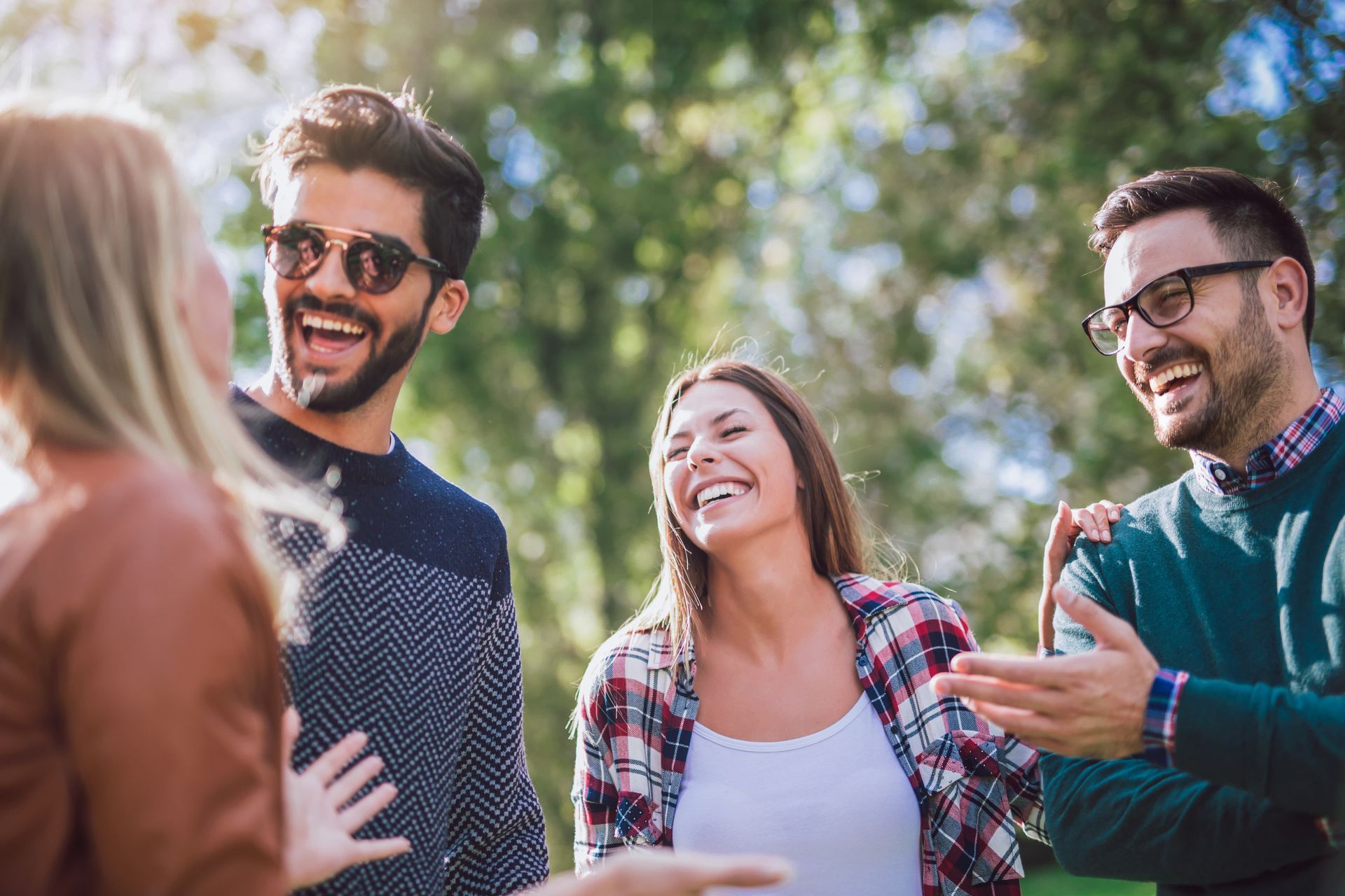Group of friends laughing outdoors, sunny day.