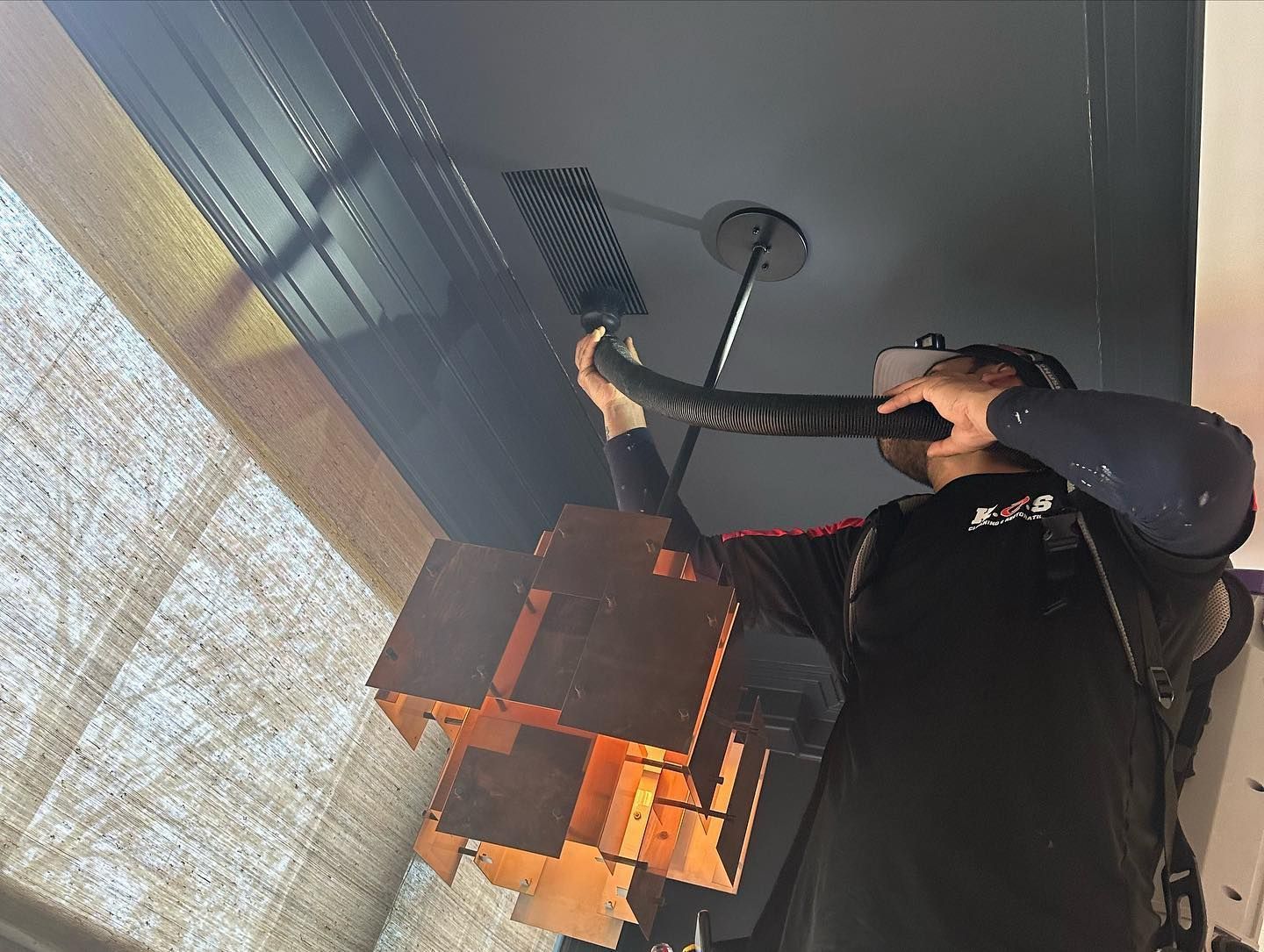 a man is cleaning ceiling air ducts with a vacuum cleaner