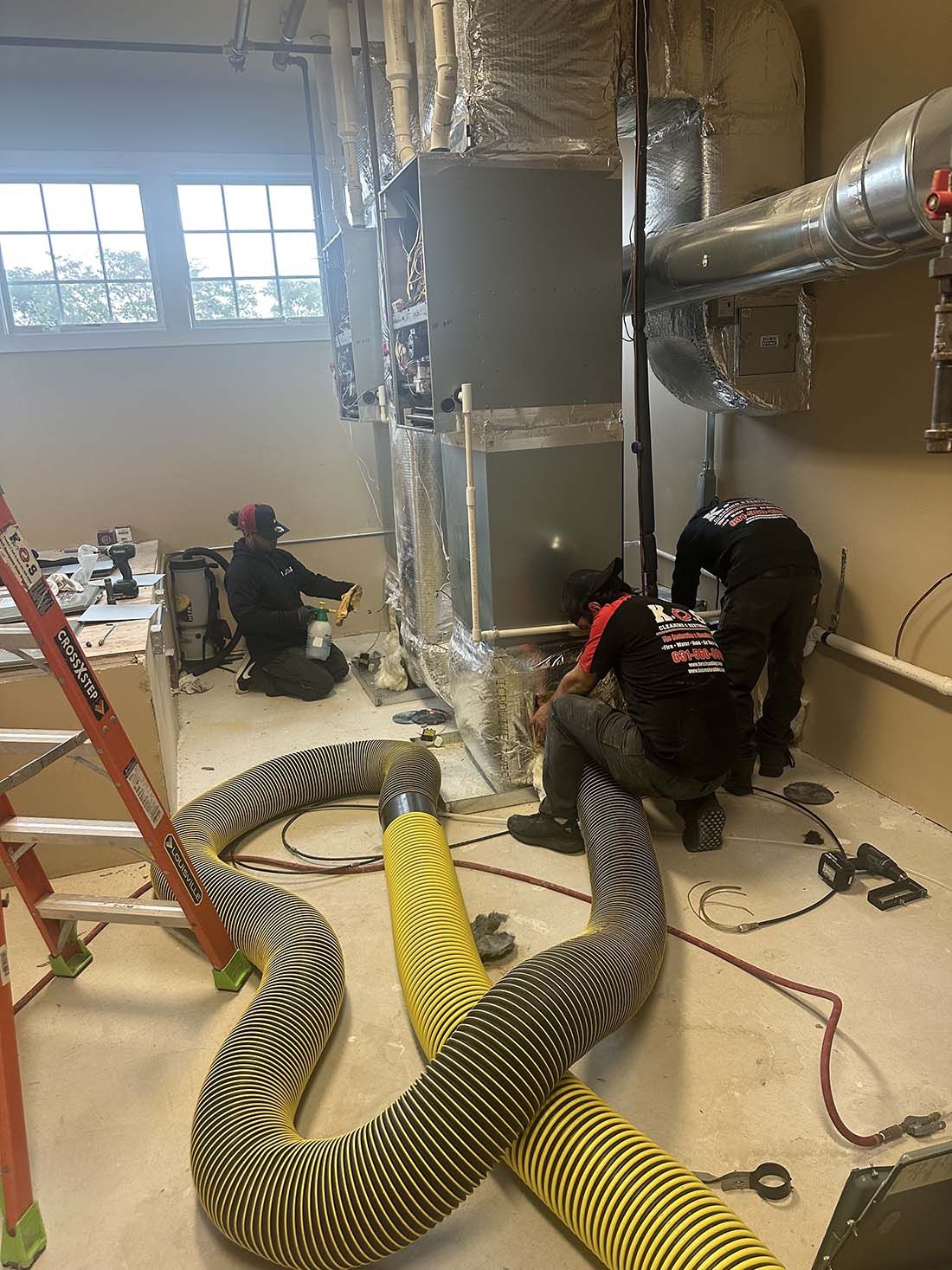 a group of people are cleaning a commercial ventilation system in a at a business on Long Island.