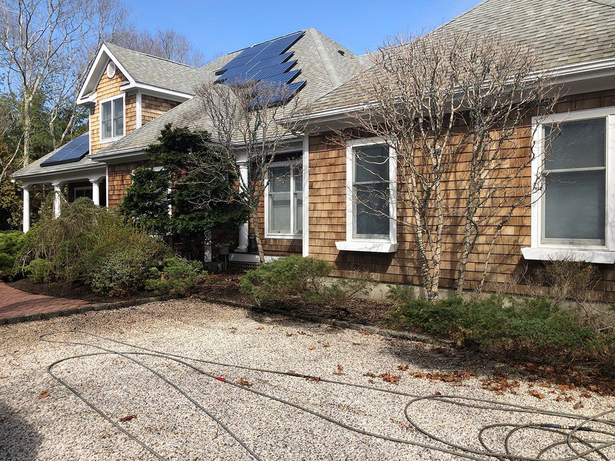 a large house with solar panels on the roof and a gravel driveway .