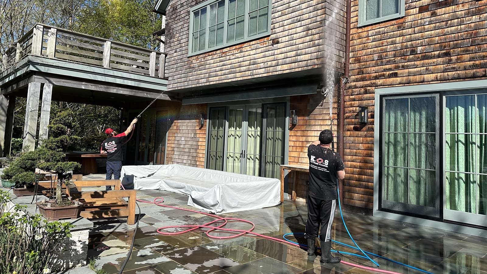 Technician soft washing green algae from vinyl siding on a Suffolk County home