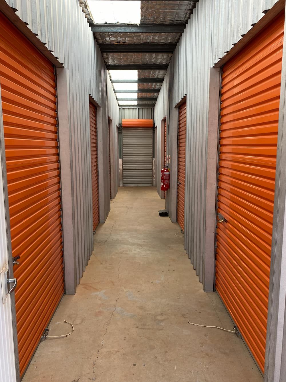 A Long Hallway With Orange Shutters On The Doors — Acacia Mini Storage in Port Macquarie, NSW