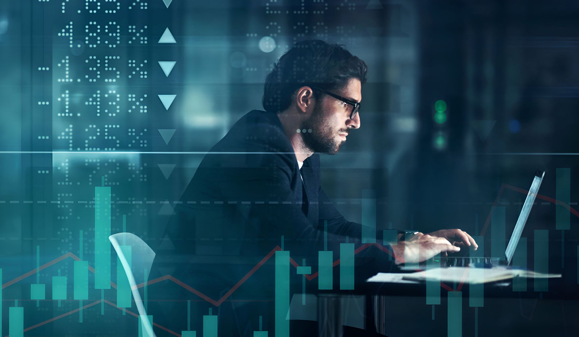 Pessoa em um escritório, sentada em frente ao notebook, analisando gráficos financeiros