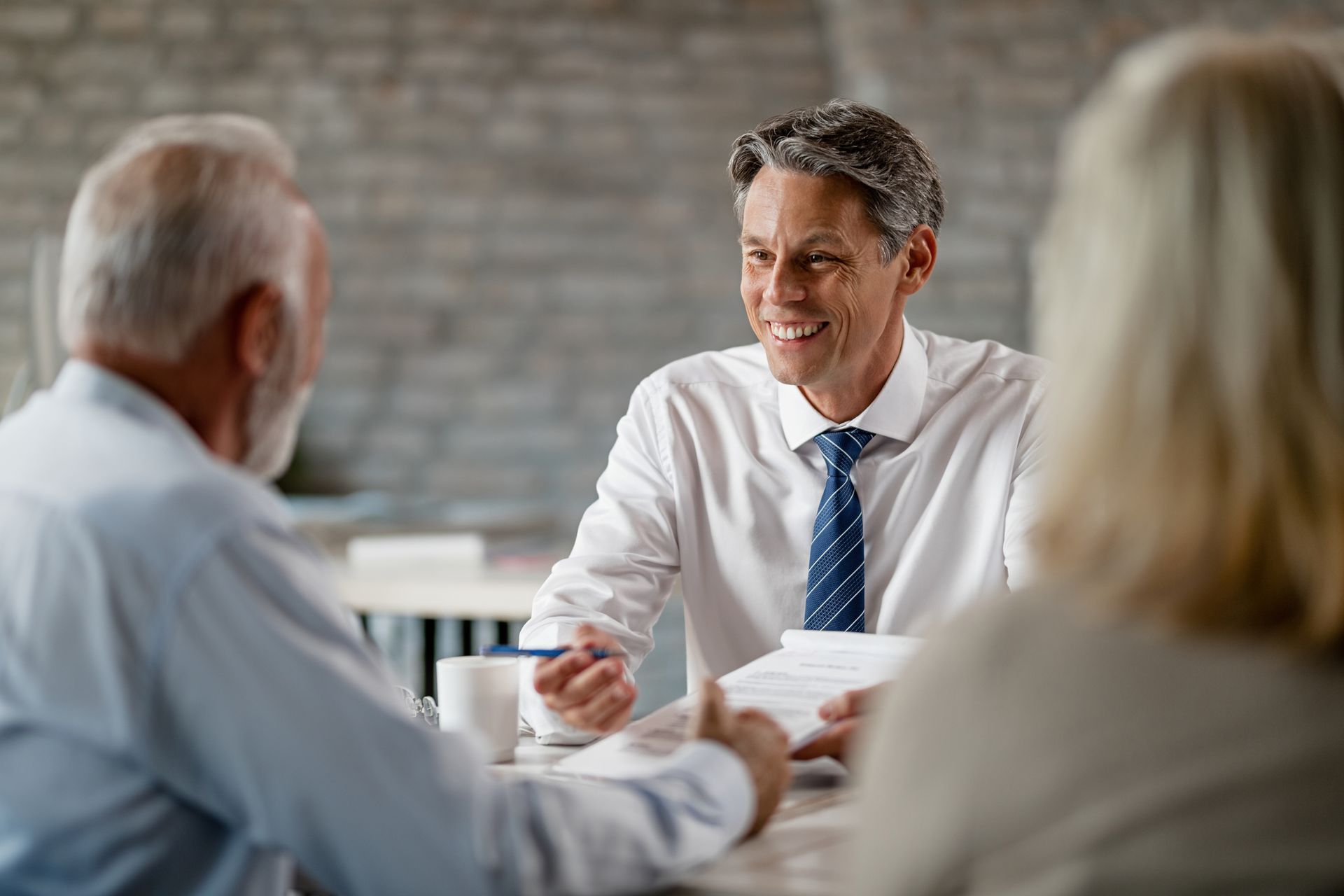 Consultor financeiro sorridente, falando sobre planos de previdência privada para seus clientes.