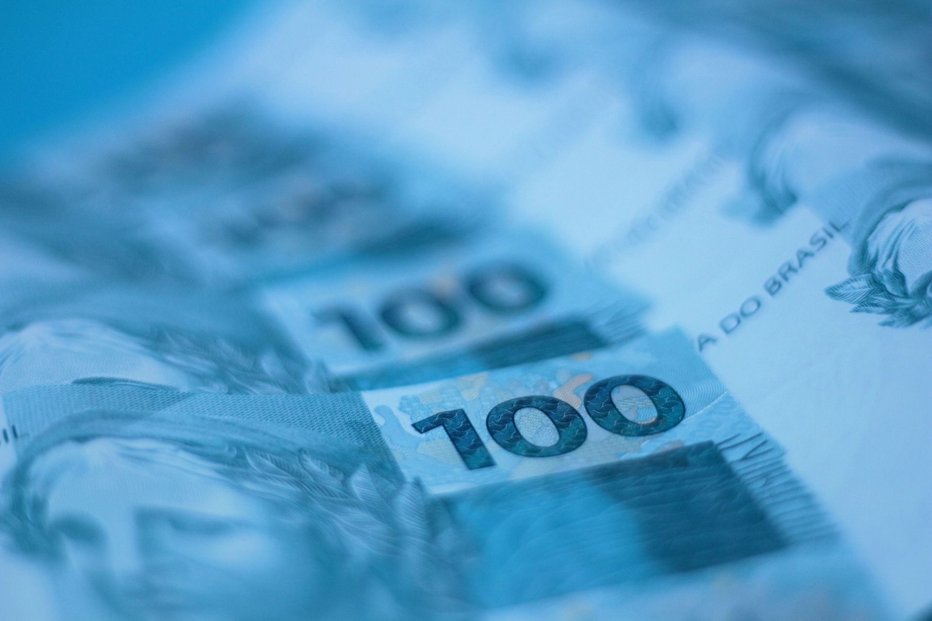 Close-up de notas de 100 reais brasileiros em tons de azul