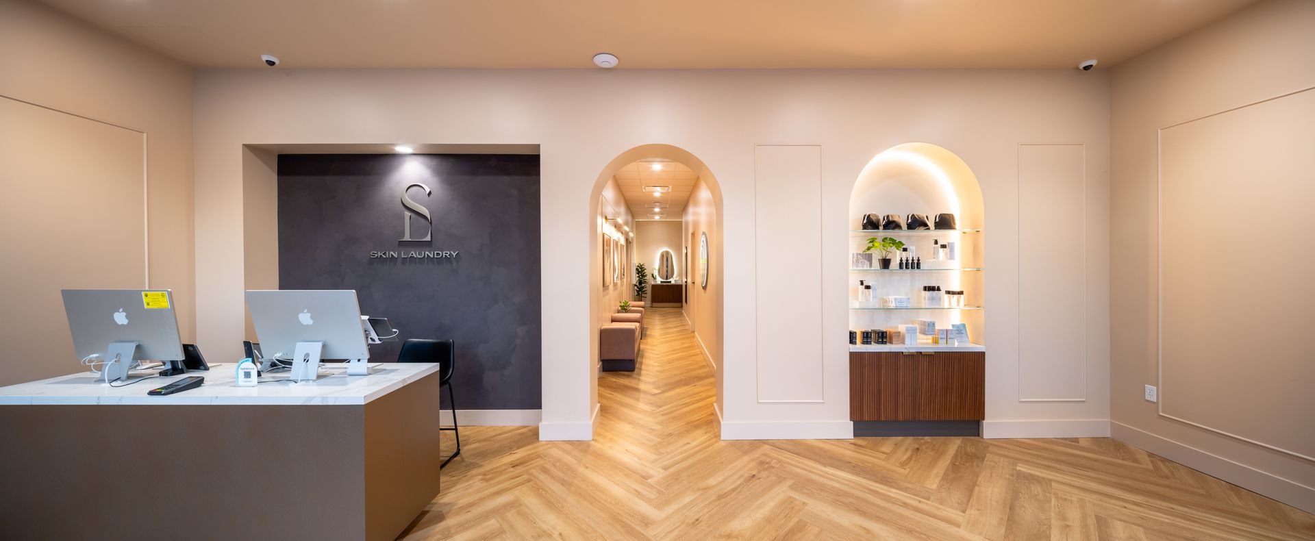 Modern jewelry store interior with display cases, arched doorway, and wood herringbone floor