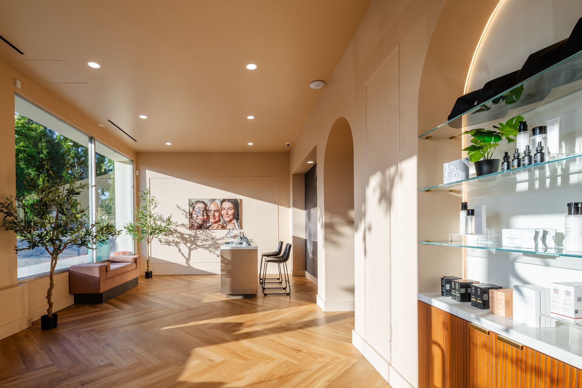 Bright modern hallway with wooden floors, arched walls, and a glass shelf displaying decor and bottles