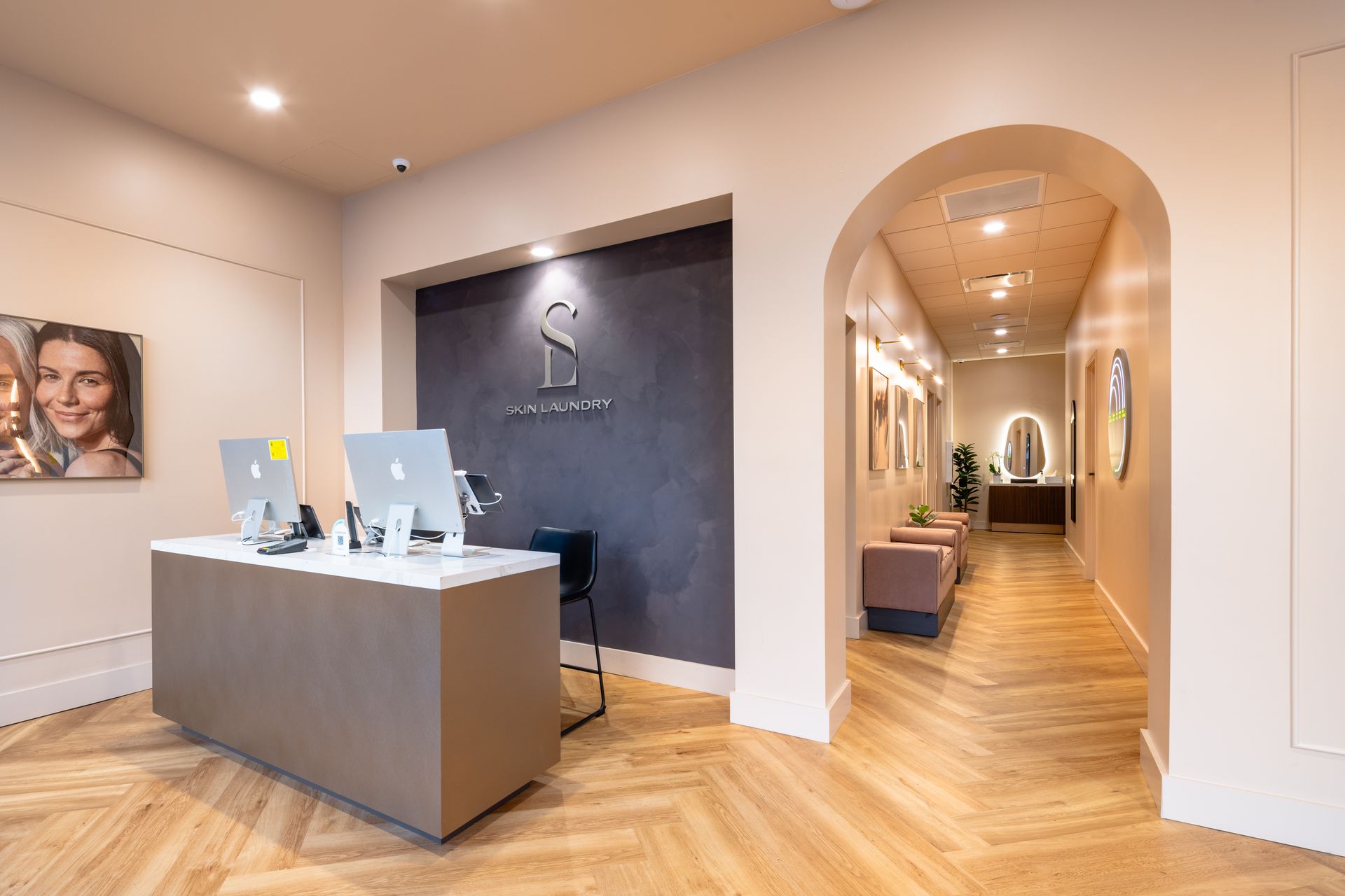 Modern reception area with a front desk, arched hallway, and warm wood flooring