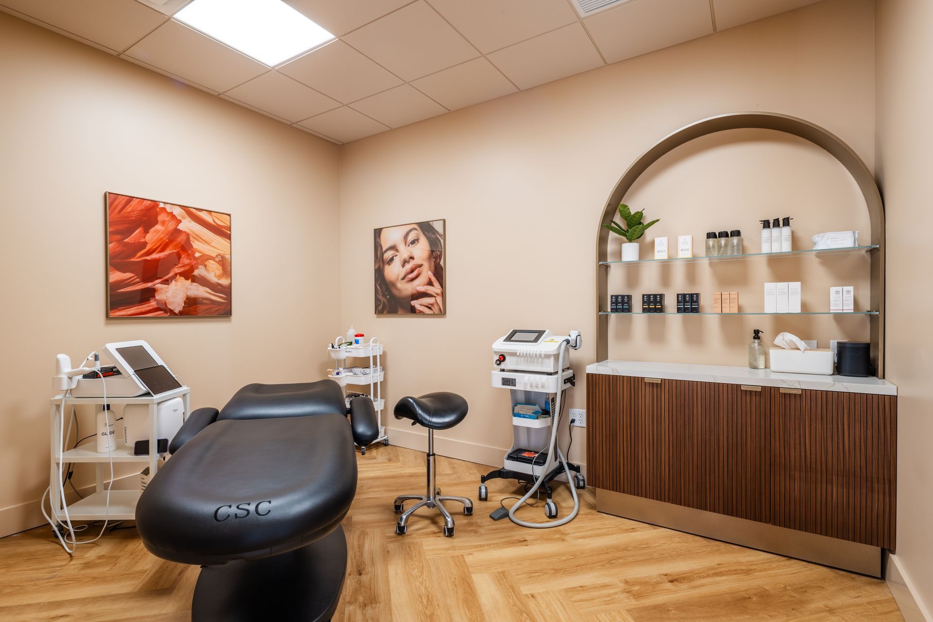 Modern medical treatment room with exam chair, equipment, and wood reception counter