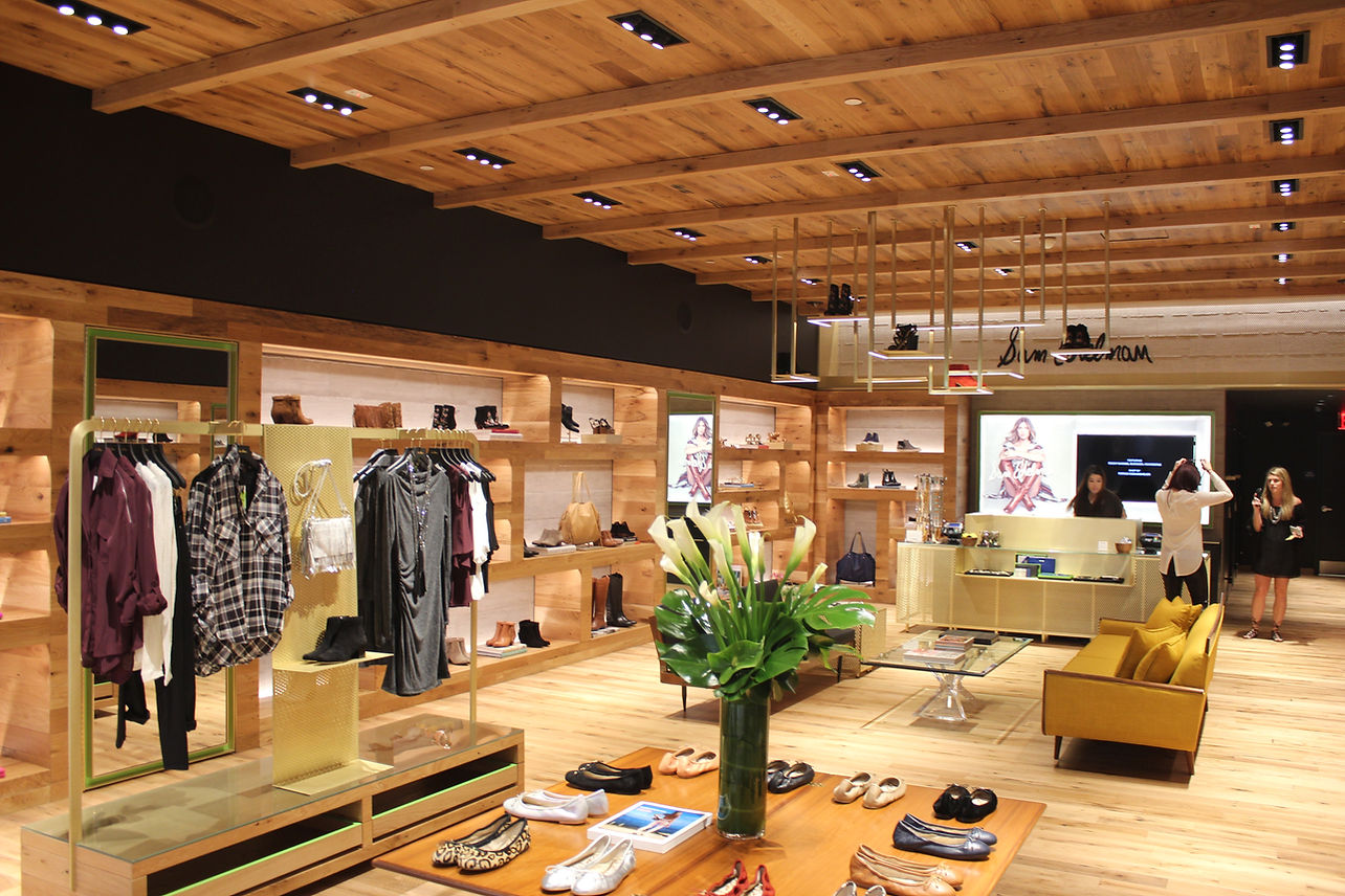 Modern clothing store interior with wooden ceiling, racks of clothes, display tables, and warm lighting