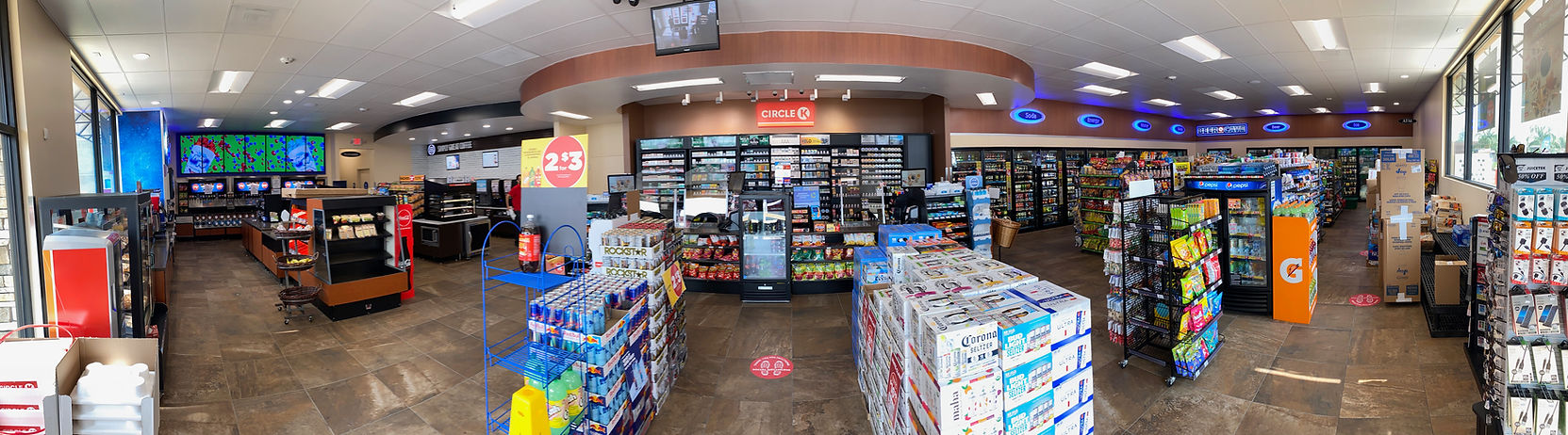 Convenience store interior with aisles of snacks, drinks, and checkout counters under bright lights