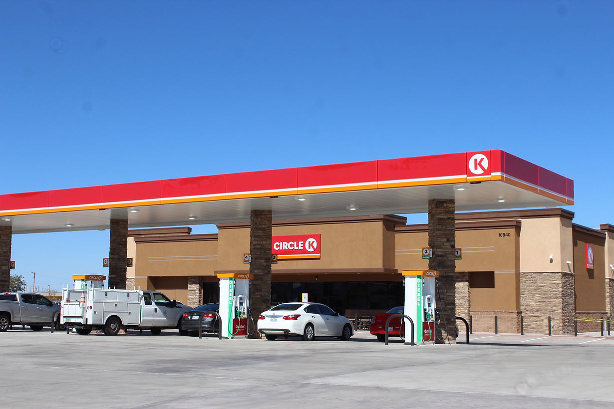Conoco gas station with red-and-white canopy, parked vehicles, and clear blue sky