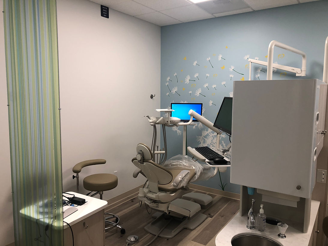 Dental exam room with chair, monitor, tools, and blue wall decor