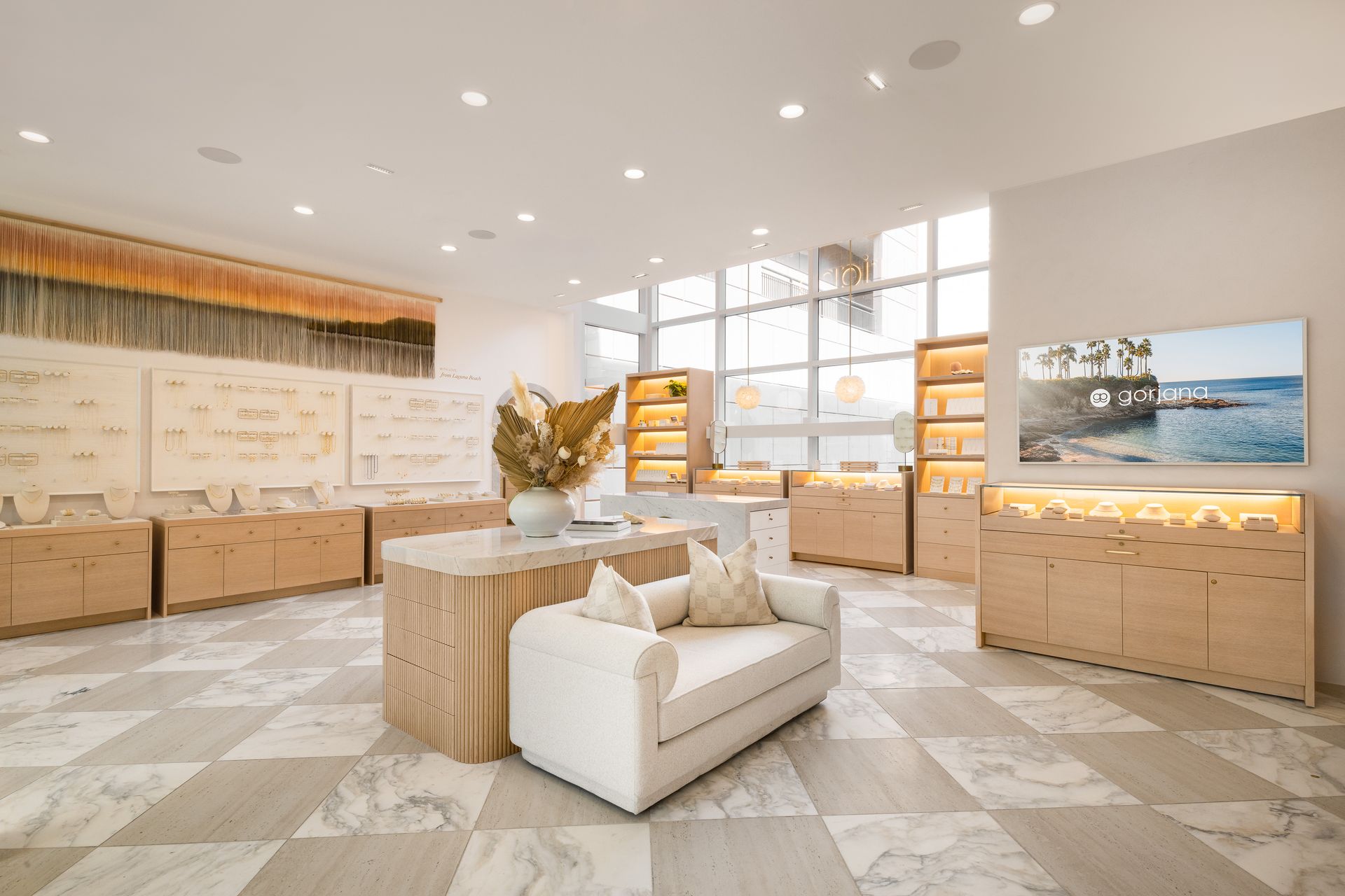Bright modern showroom with sofas, display walls, and wood cabinetry in a spacious sunlit room