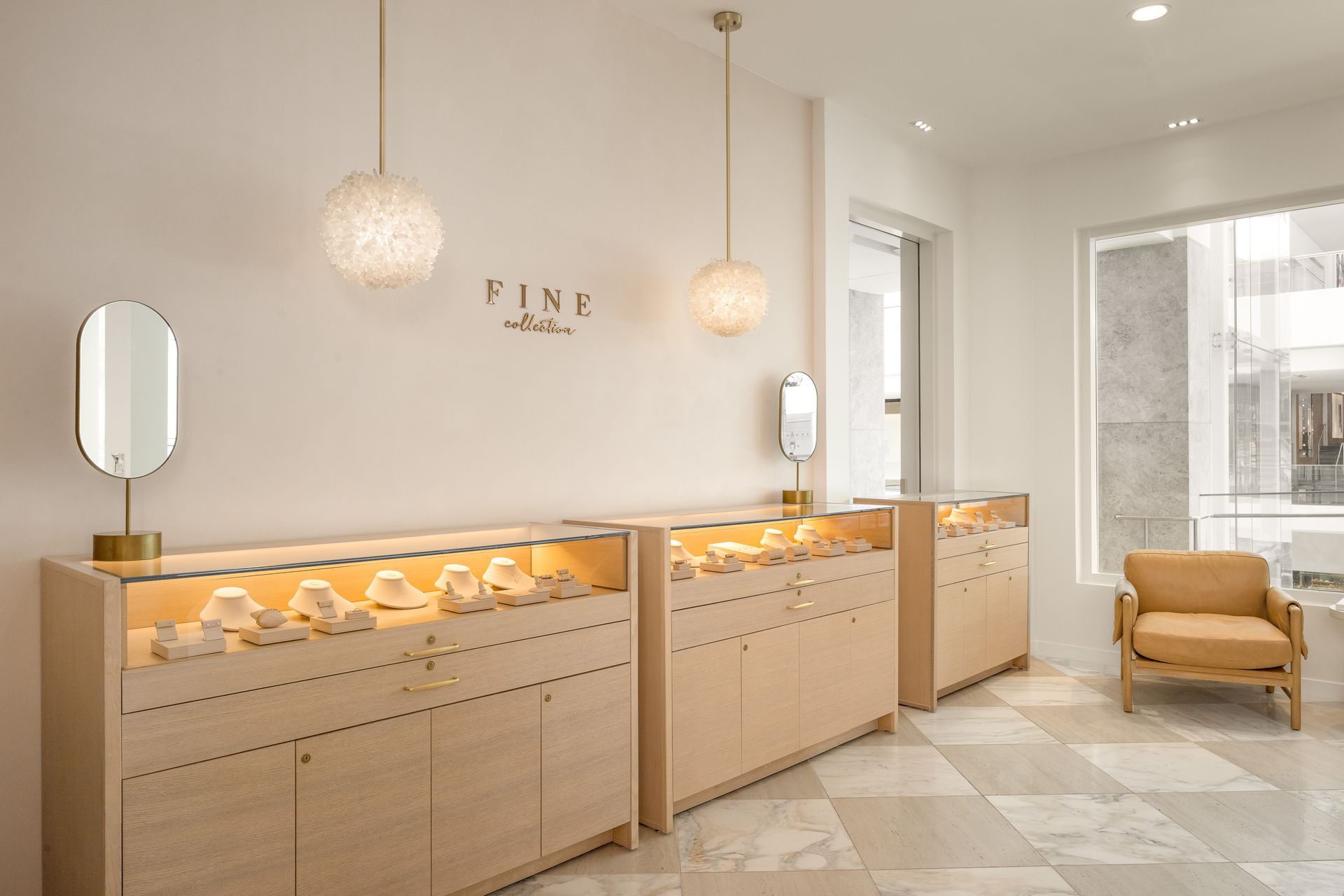 Bright boutique pastry shop interior with glass display cases, pendant lights, and a lounge chair