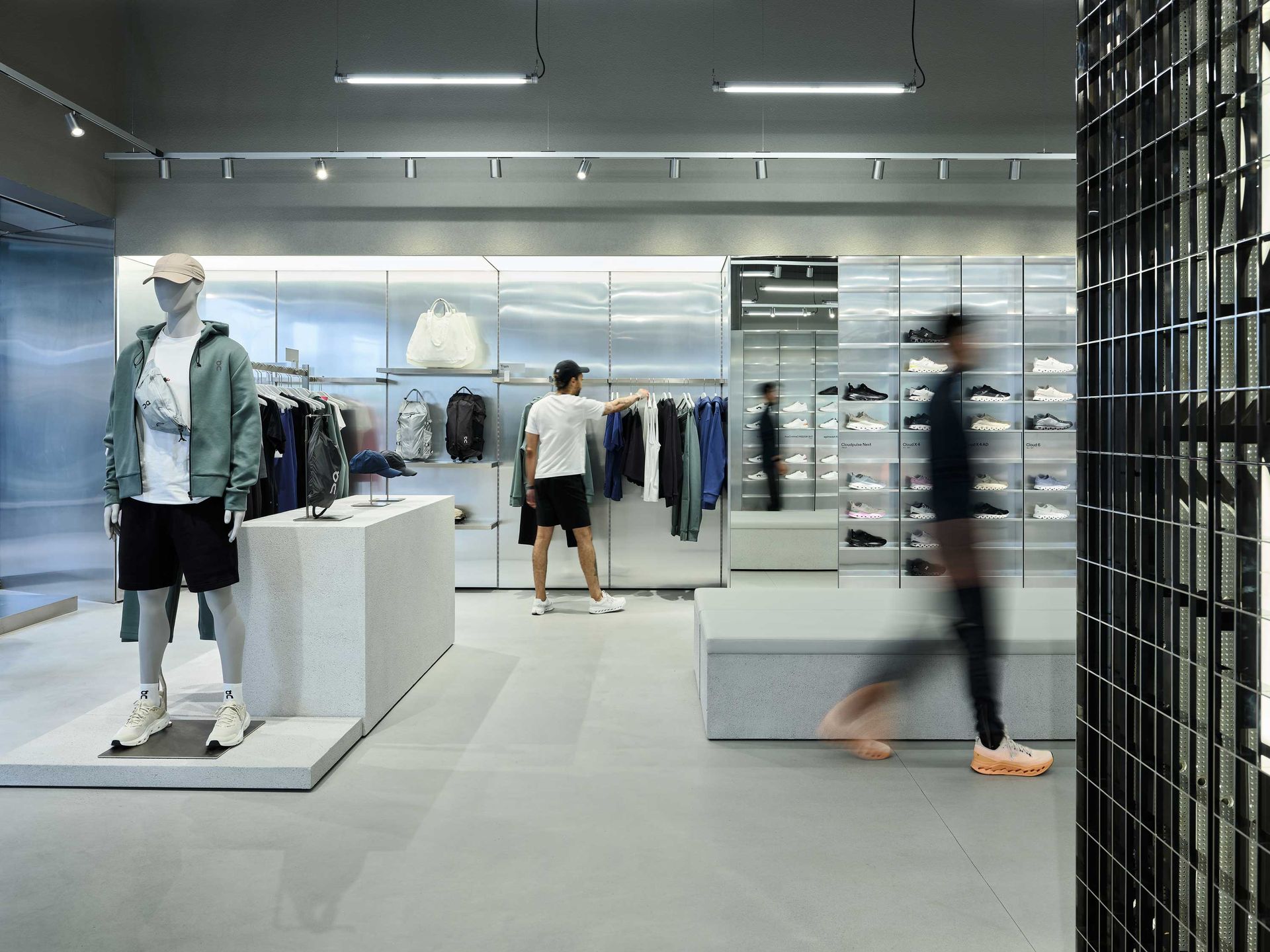 Clothing store interior with mannequins, folded apparel displays, and shoppers browsing racks