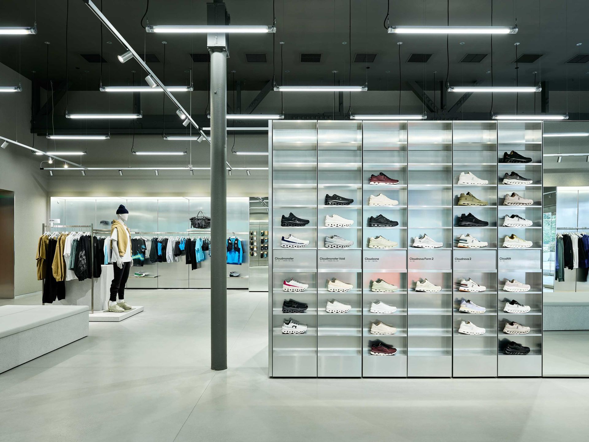 Modern sneaker store interior with wall displays of shoes and clothing racks under bright lights