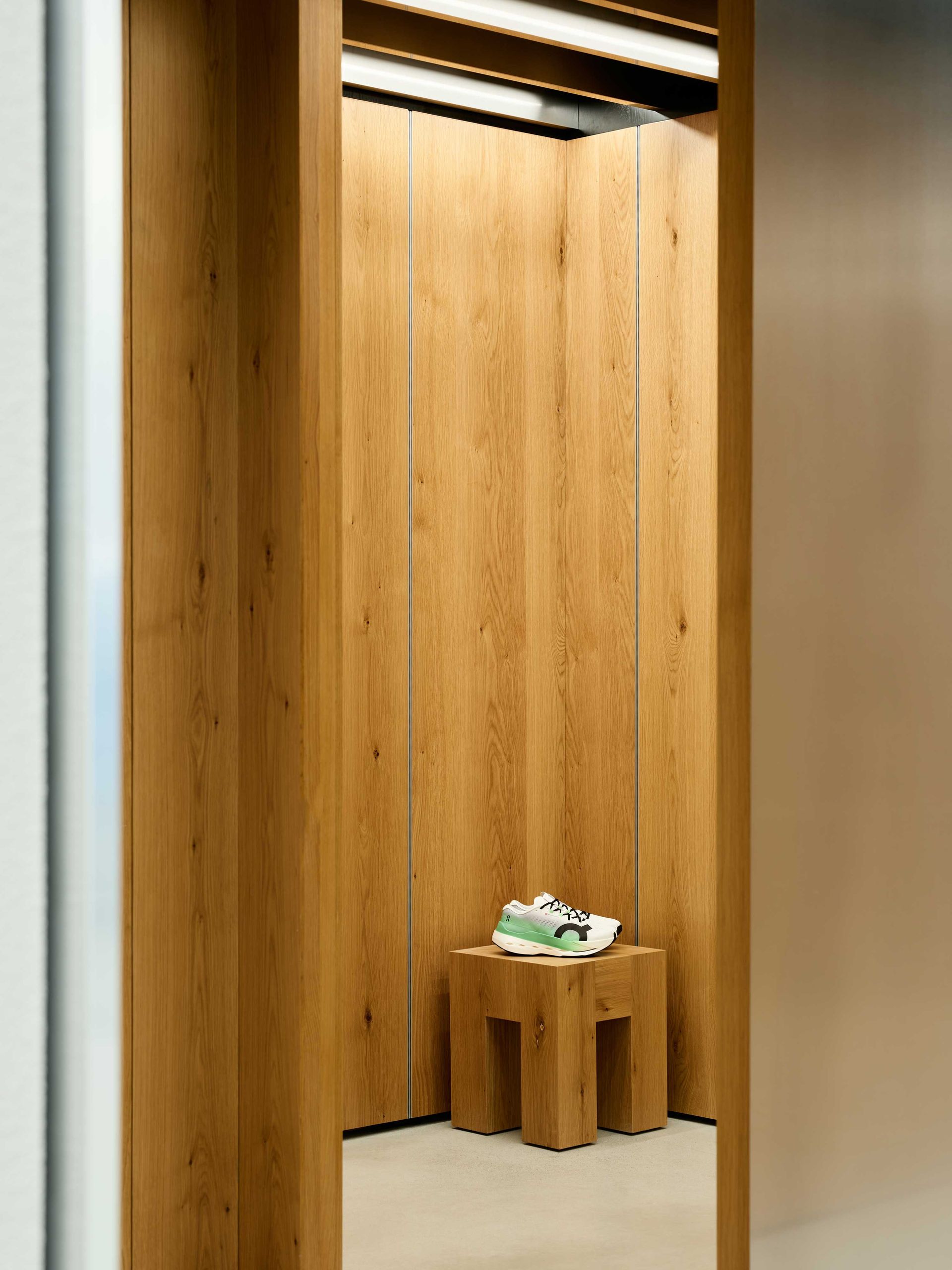 Wood-paneled elevator with a small wooden stool holding a folded towel or cloth.