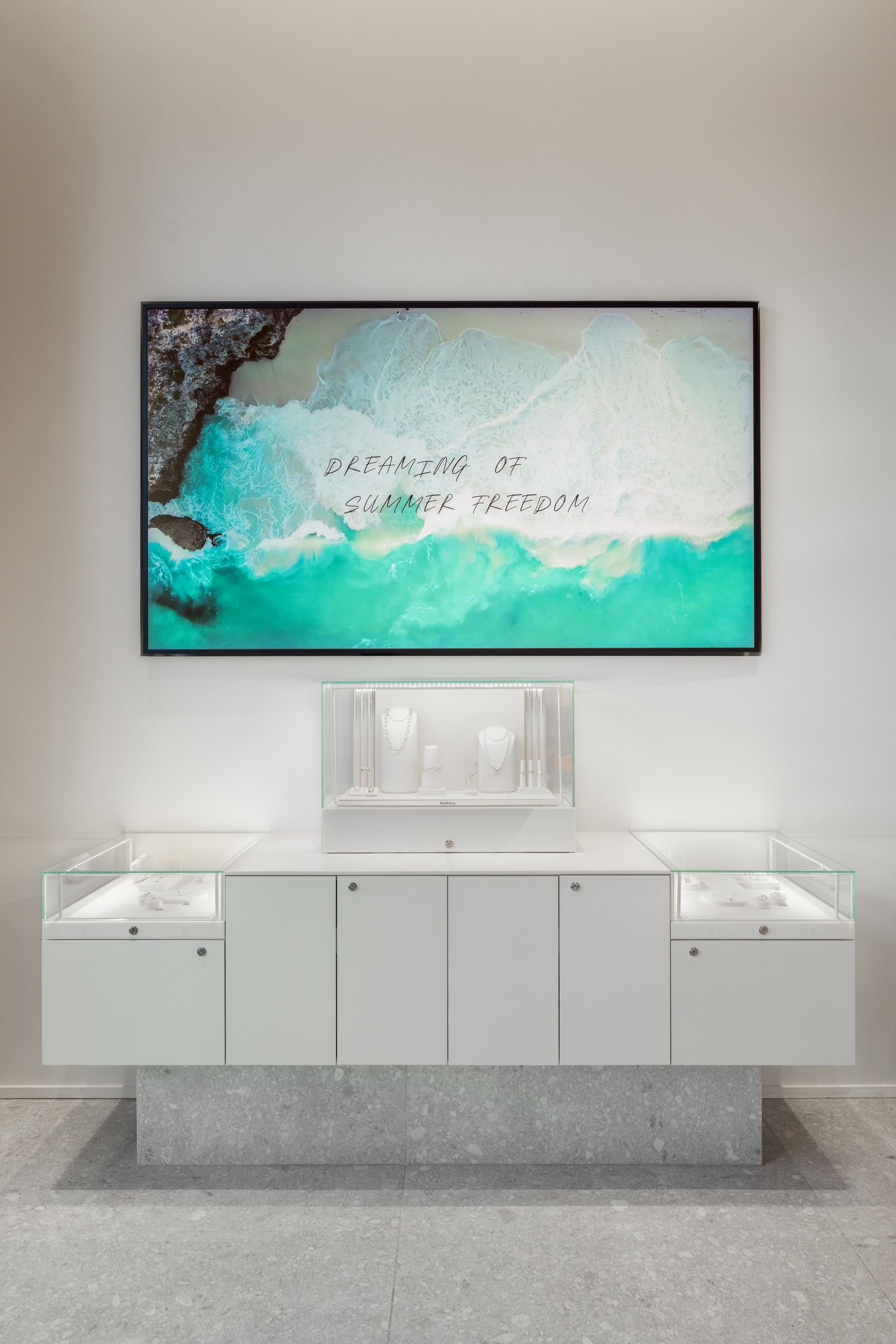 Modern white vanity with mirror and wall-mounted TV displaying a turquoise beach scene