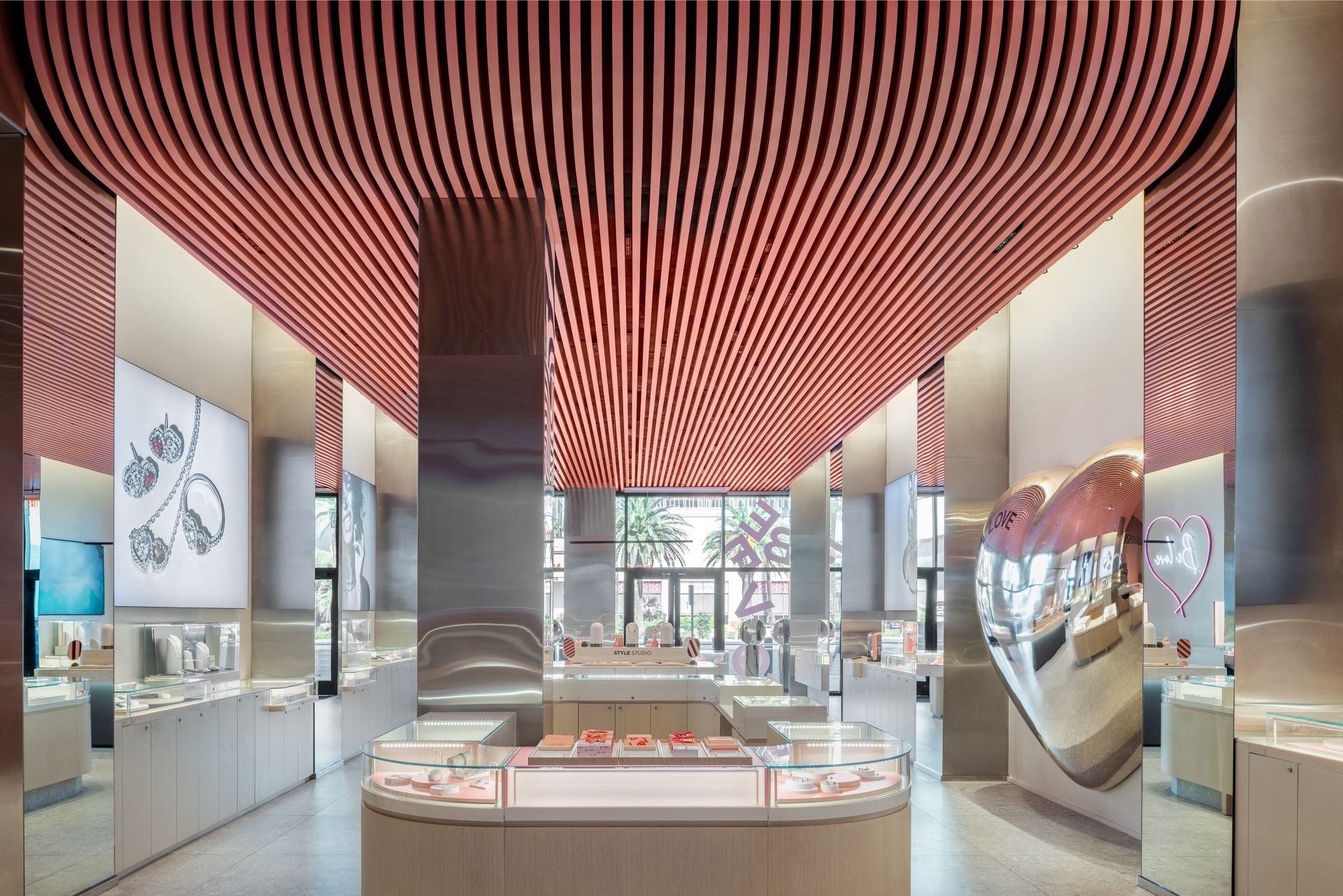 Modern showroom interior with red striped ceiling, glass displays, and mirrored columns