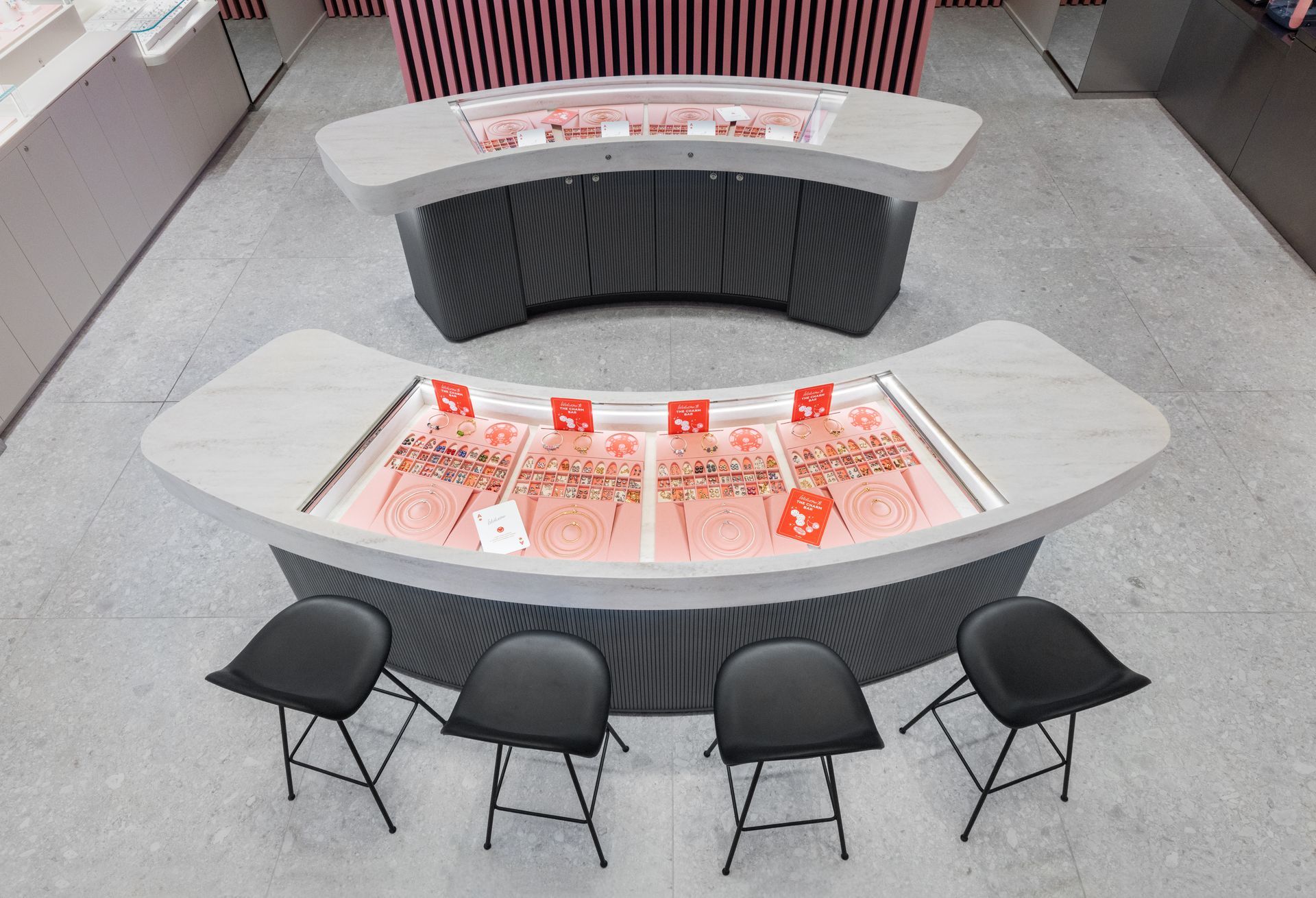 Curved display table with red-and-white items and four black folding chairs in a showroom