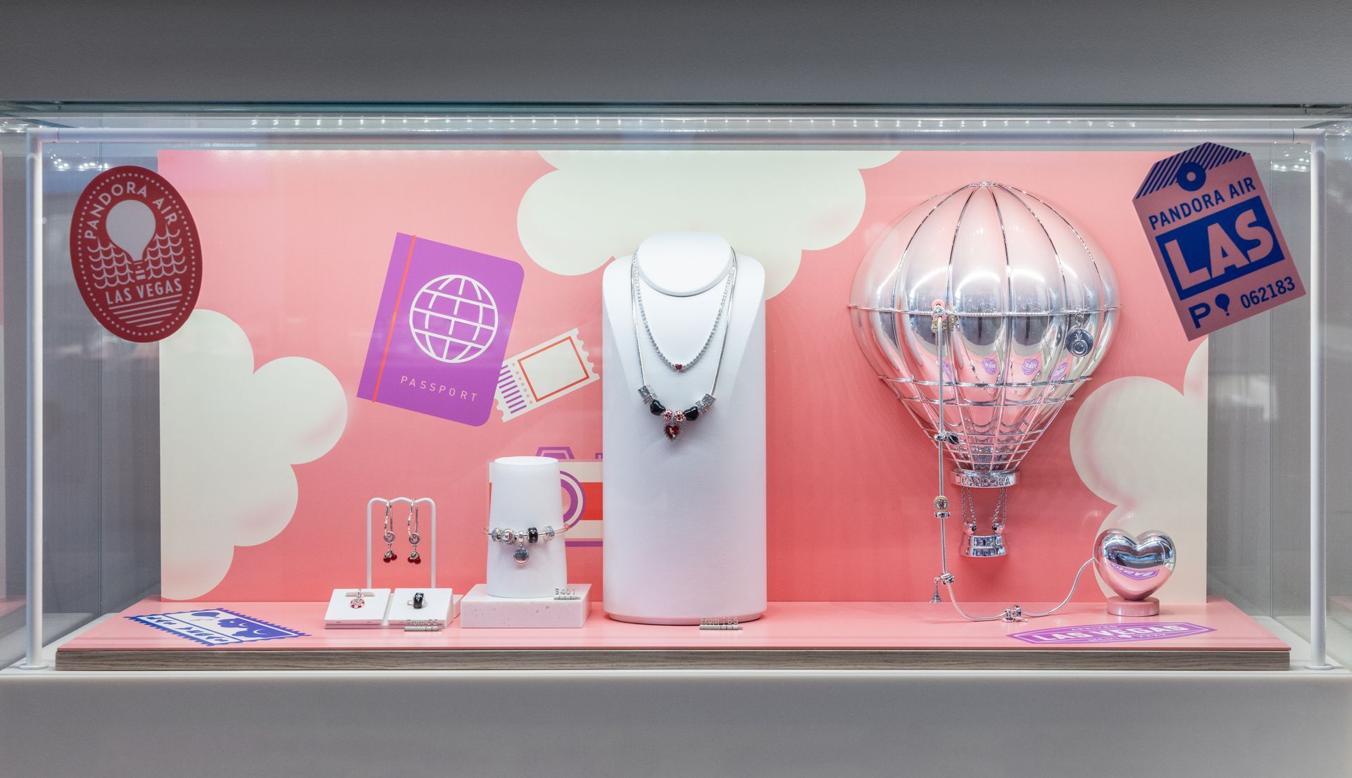 Jewelry store display with pink background, necklaces, earrings, rings, and decorative glass pieces