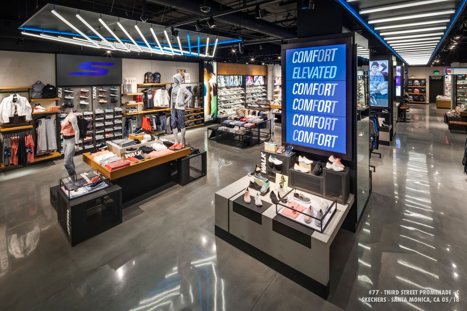 Bright sporting goods store interior with shoes, apparel displays, and a tall blue Nike signboard