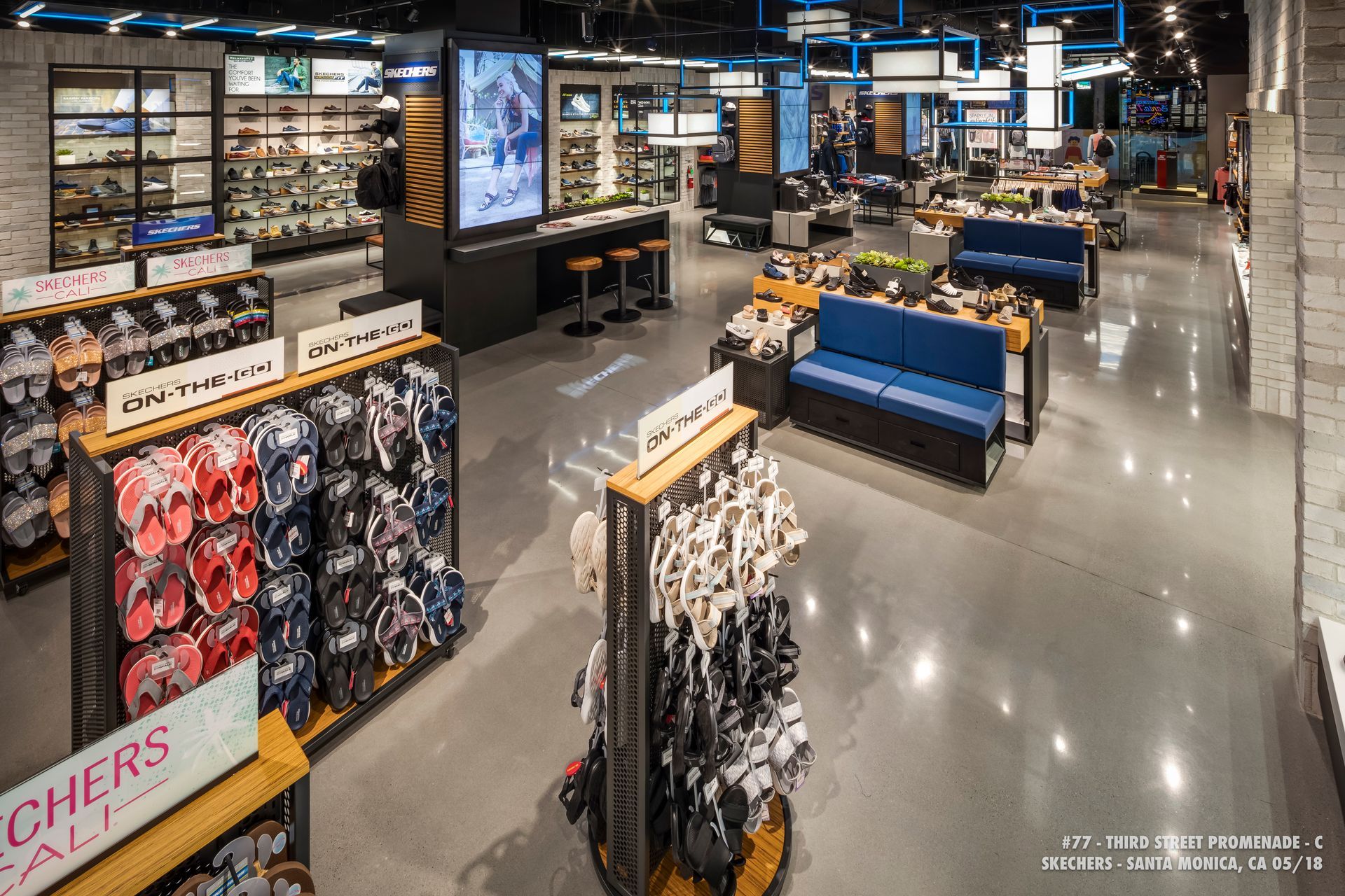 Clothing store interior with racks of socks and apparel, blue benches, and wall displays under bright lights