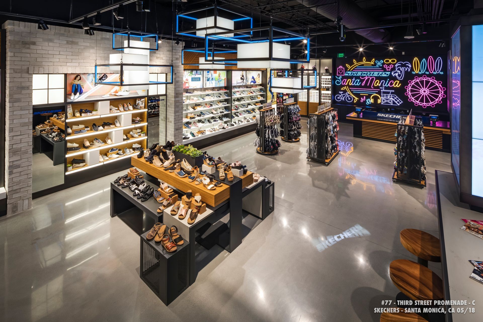 Modern sneaker store interior with illuminated shelves, display tables, and colorful wall art