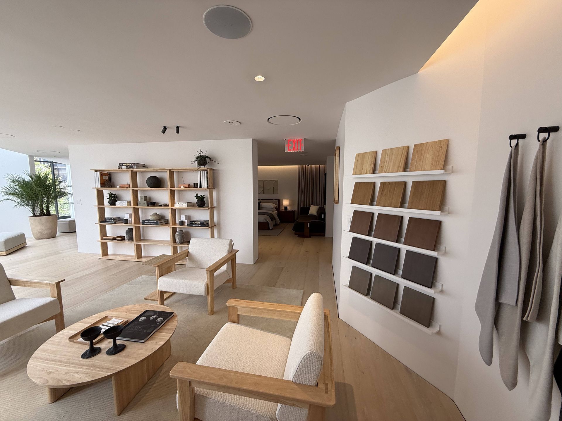 Bright minimalist lounge with white walls, wood shelves, woven chairs, and framed art on the wall