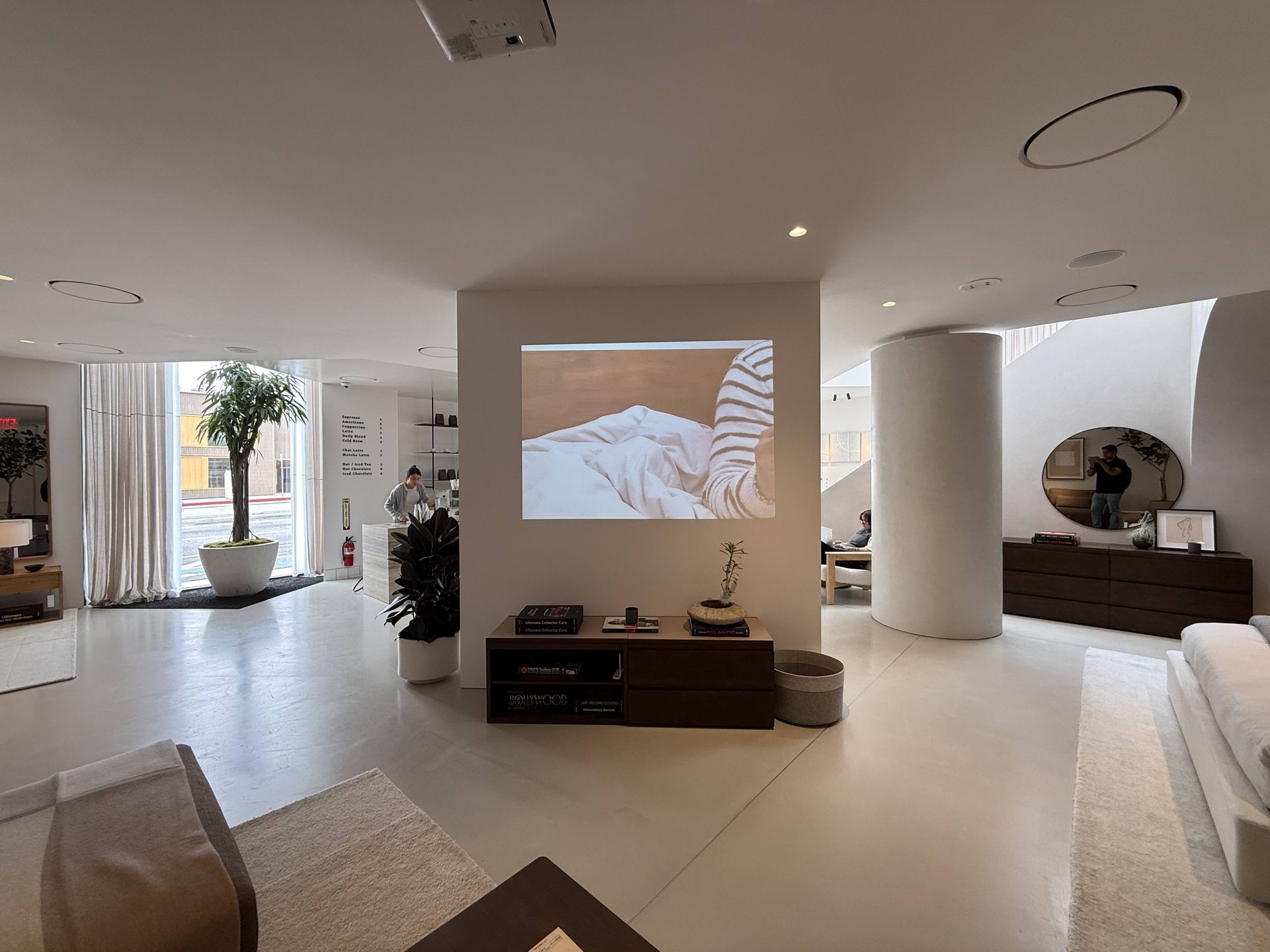 Modern living room with a projector screen, white columns, and minimalist decor