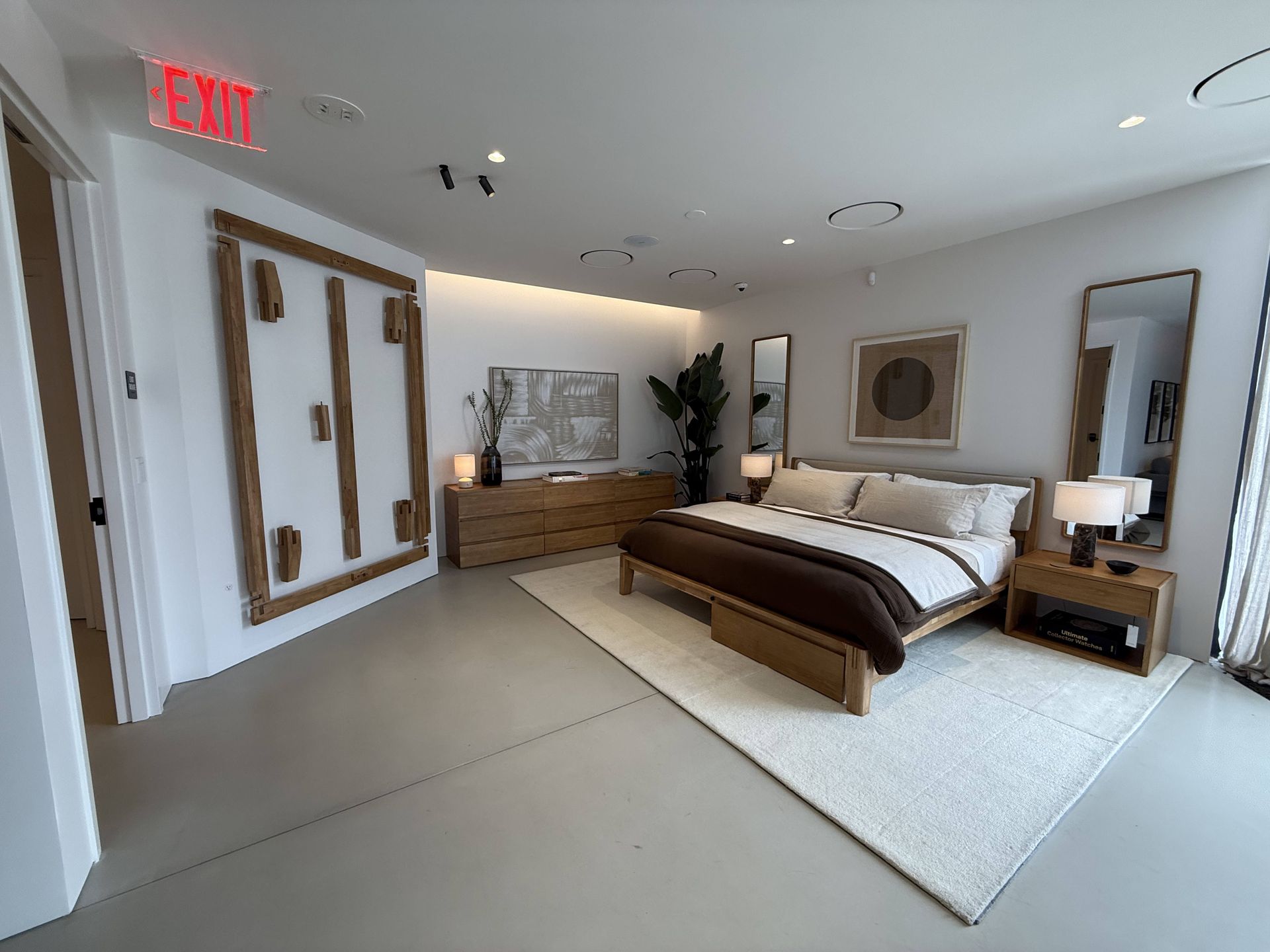 Modern bedroom with bed, dresser, mirror, rug, and wall art in a bright neutral space