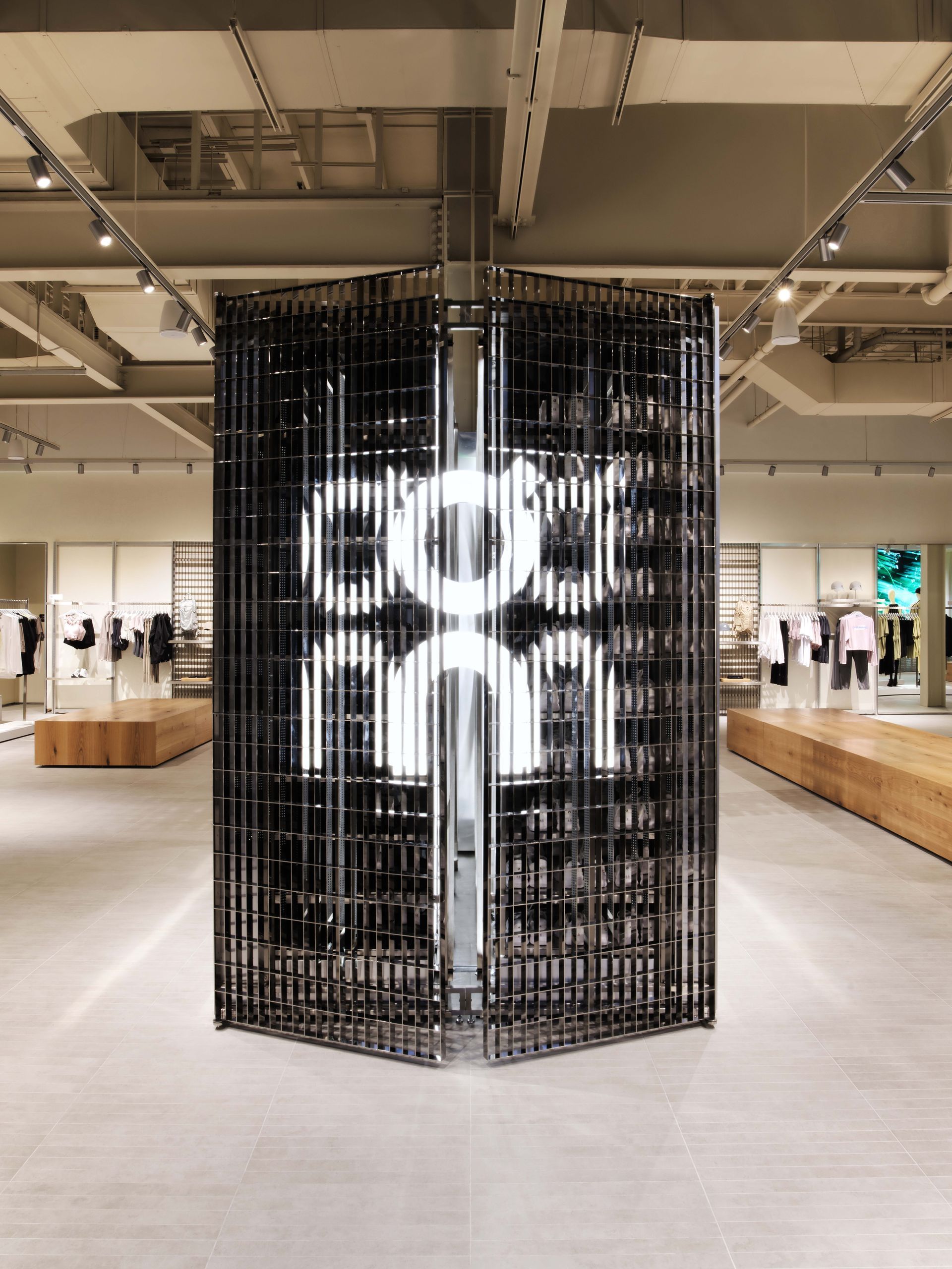 Large black cylindrical art installation with glowing white letters in a bright gallery space