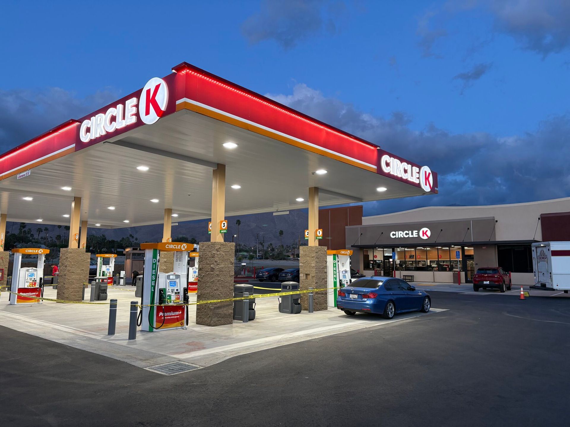 Circle K gas station at dusk with lit pumps, a blue car, and a convenience store canopy
