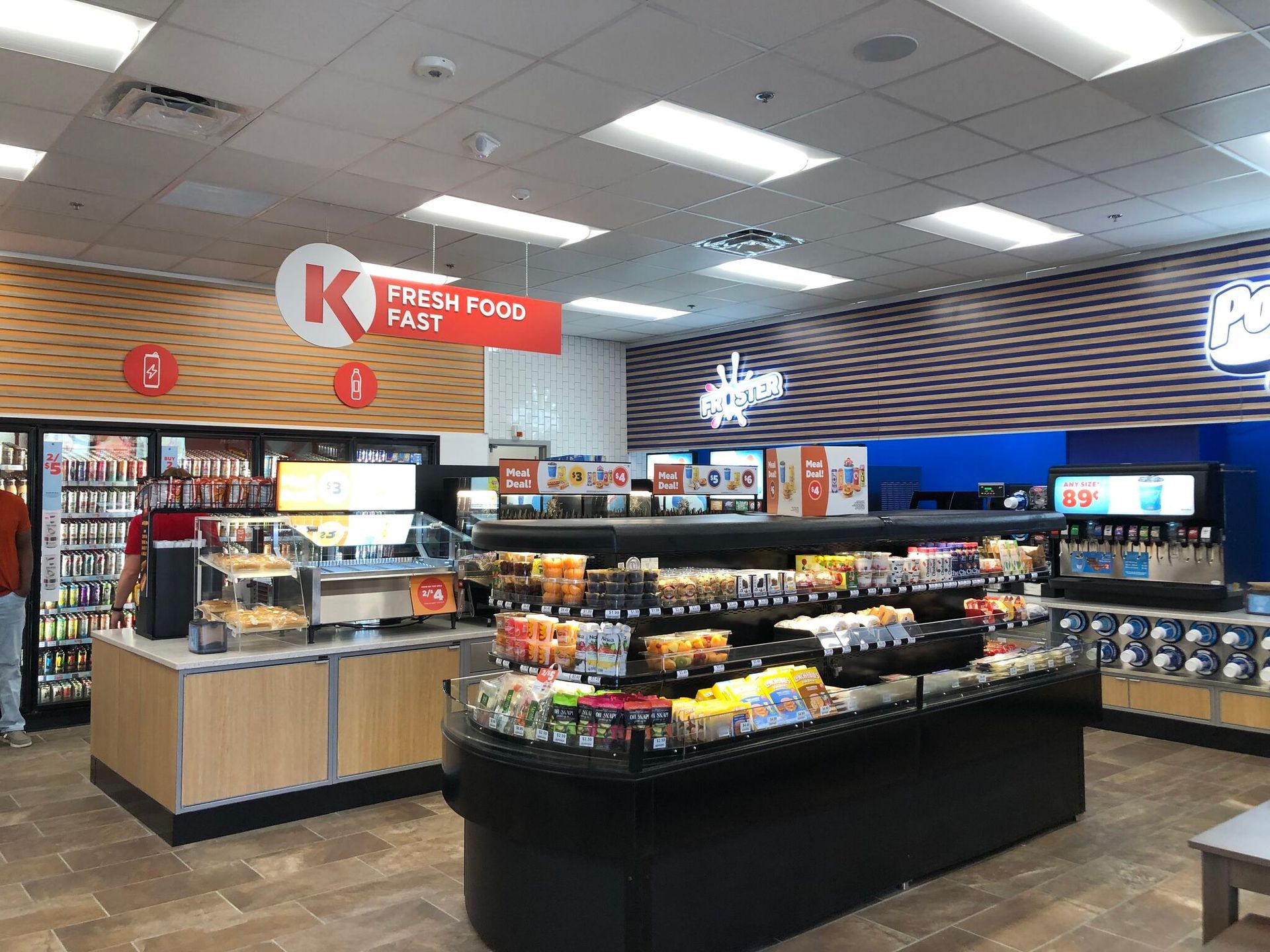 Convenience store interior with snack aisles, refrigerated drinks, and a checkout counter